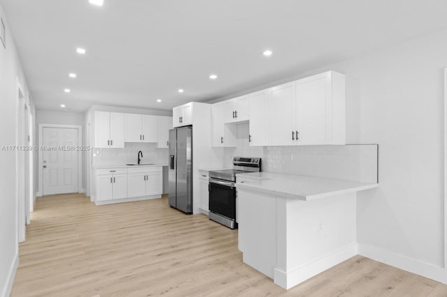 kitchen featuring white cabinets, appliances with stainless steel finishes, light hardwood / wood-style floors, and kitchen peninsula