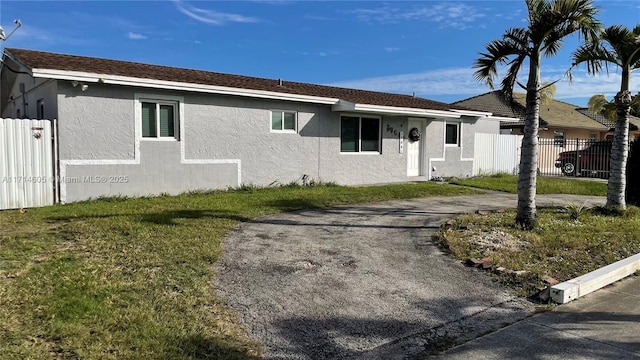 view of front of home featuring stucco siding, fence, and a front yard