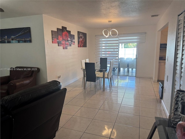 dining area featuring light tile patterned floors, baseboards, visible vents, a textured ceiling, and a chandelier