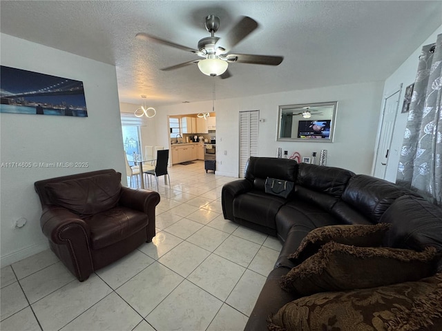 living area with a textured ceiling, light tile patterned floors, a ceiling fan, and baseboards