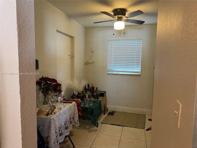 dining area with a ceiling fan, tile patterned flooring, and baseboards