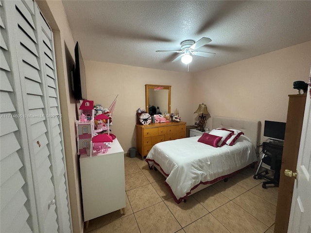 bedroom featuring light tile patterned floors, ceiling fan, and a textured ceiling