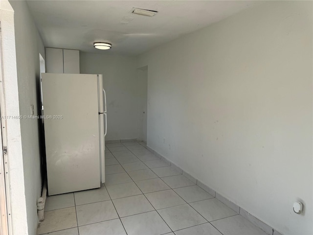 kitchen with light tile patterned floors, white cabinets, and freestanding refrigerator