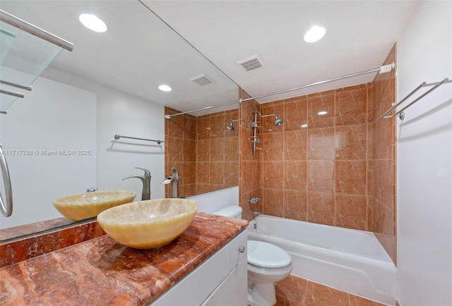 full bathroom featuring tile patterned flooring, vanity, tiled shower / bath combo, and toilet