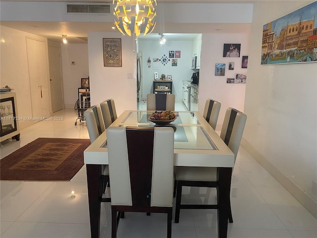 dining room with tile patterned flooring, an inviting chandelier, baseboards, and visible vents