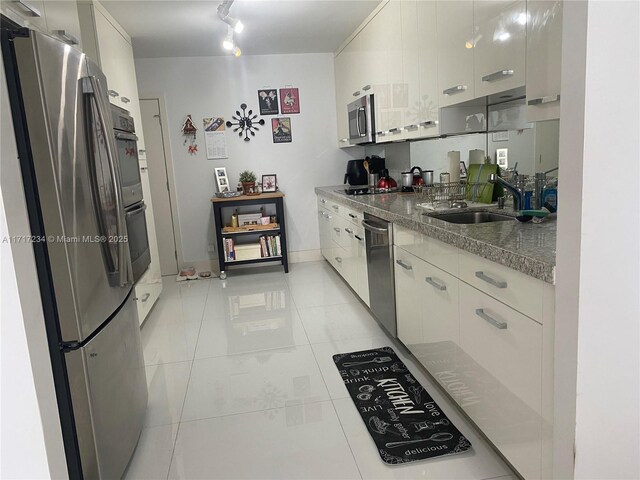 kitchen featuring stainless steel refrigerator, light tile patterned floors, a notable chandelier, black electric stovetop, and white cabinets