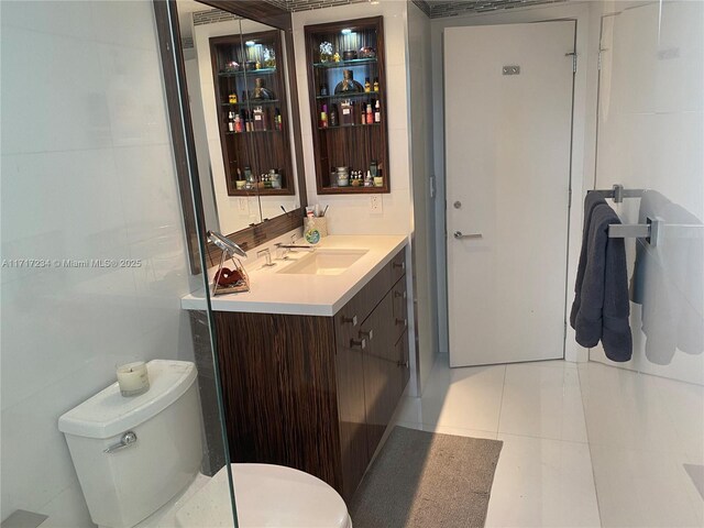 bathroom featuring a tile shower, vanity, tile walls, tile patterned flooring, and toilet