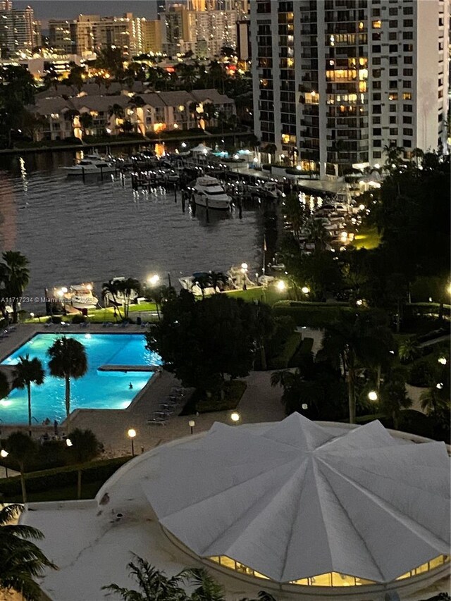 pool at night featuring a water view