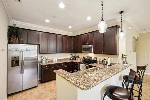 kitchen with hanging light fixtures, dark brown cabinetry, stainless steel appliances, sink, and kitchen peninsula