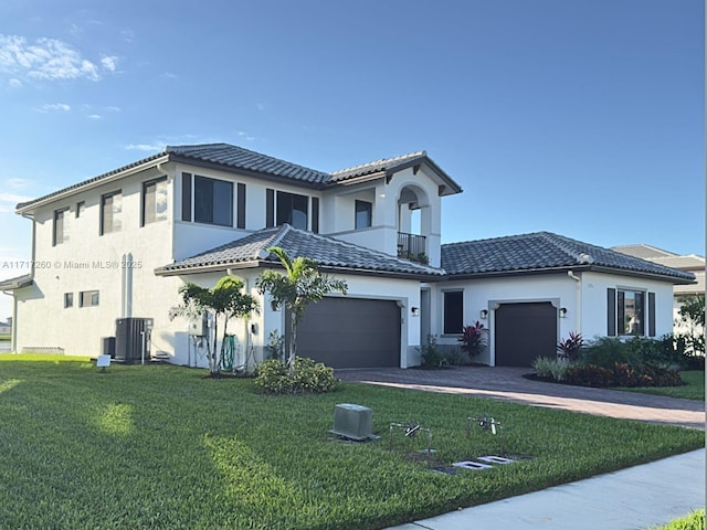 mediterranean / spanish home with central AC unit, a balcony, a garage, and a front lawn