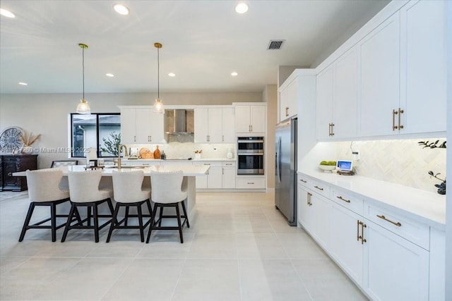 kitchen featuring white cabinets, pendant lighting, and wall chimney range hood