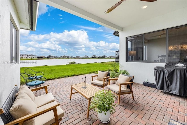 view of patio featuring grilling area, ceiling fan, and a water view