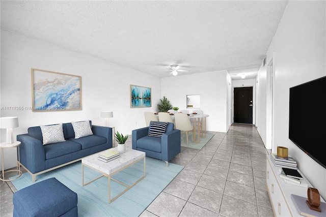 living room with ceiling fan, light tile patterned flooring, and a textured ceiling