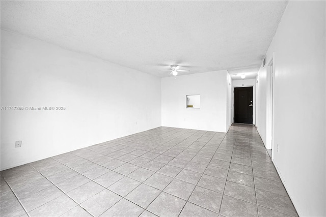 unfurnished room with ceiling fan, light tile patterned flooring, and a textured ceiling