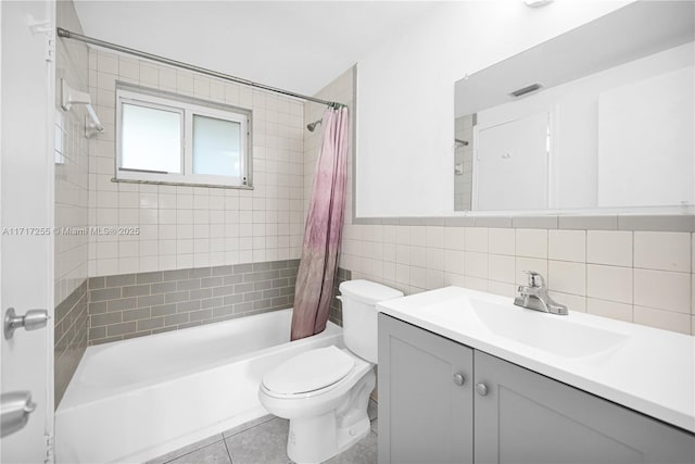 full bathroom with vanity, shower / tub combo with curtain, tile walls, tile patterned flooring, and toilet