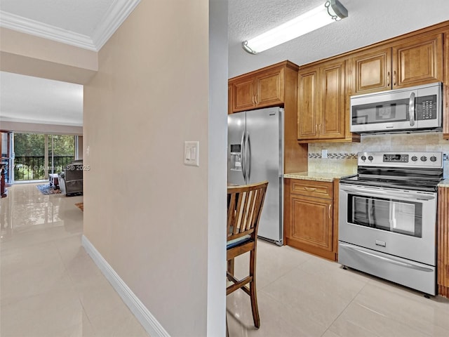 kitchen featuring stainless steel appliances, light stone counters, crown molding, a textured ceiling, and light tile patterned floors