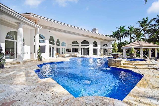 view of swimming pool featuring a gazebo, ceiling fan, pool water feature, an in ground hot tub, and a patio