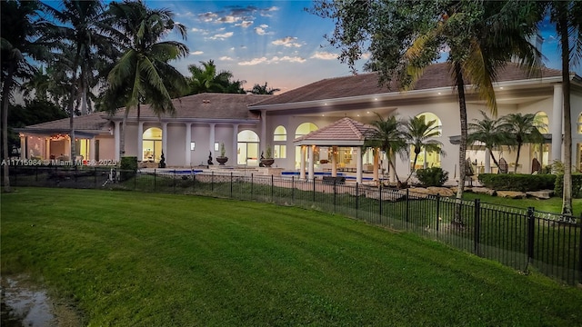 back house at dusk with a lawn