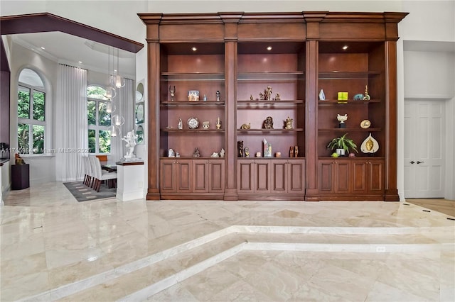 bar with pendant lighting, built in shelves, light stone countertops, and ornamental molding