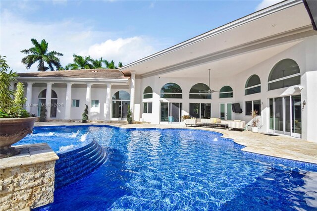 pool at dusk with ceiling fan, an outdoor hangout area, pool water feature, a gazebo, and a patio area