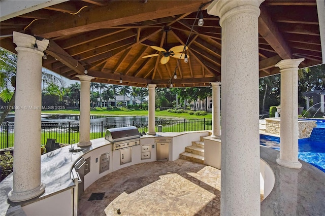 view of patio with ceiling fan, exterior kitchen, a gazebo, area for grilling, and a water view