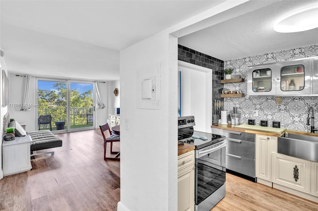 kitchen featuring butcher block countertops, expansive windows, appliances with stainless steel finishes, and light hardwood / wood-style flooring