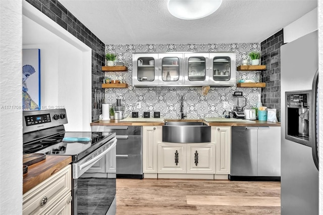 kitchen featuring wooden counters, appliances with stainless steel finishes, a textured ceiling, and sink