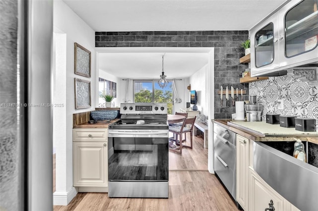 kitchen featuring an inviting chandelier, backsplash, pendant lighting, light hardwood / wood-style floors, and electric stove