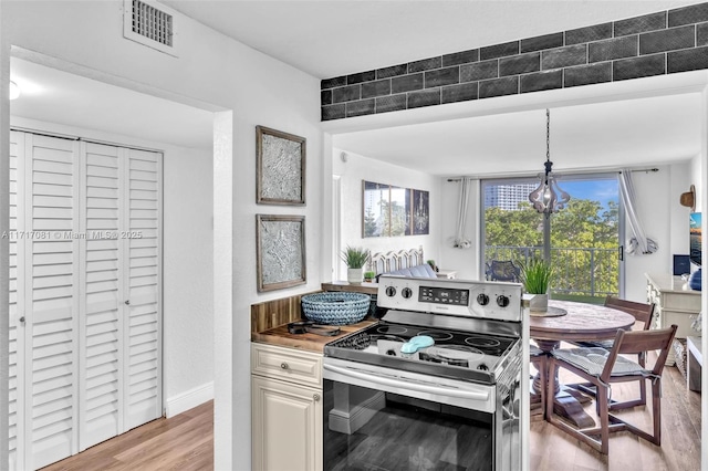 kitchen with electric stove, light hardwood / wood-style flooring, a chandelier, and decorative light fixtures