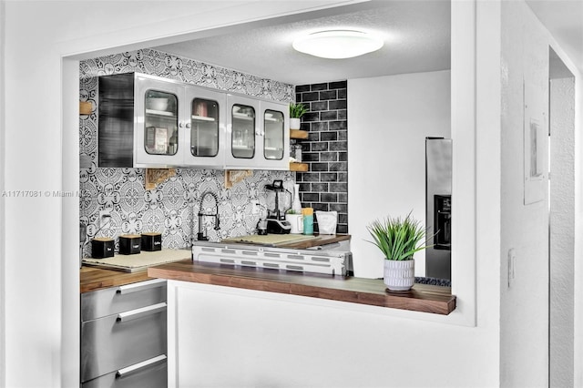 bar with butcher block counters, a textured ceiling, and tasteful backsplash