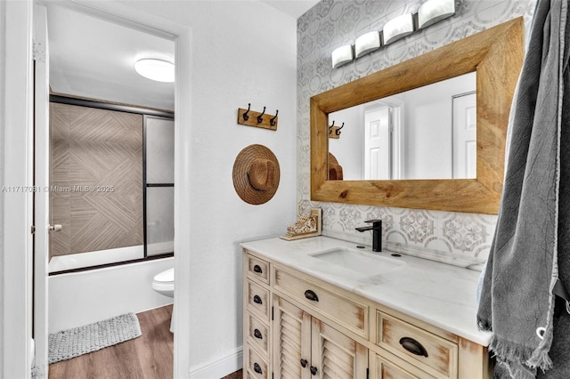 full bathroom with wood-type flooring, vanity, toilet, and enclosed tub / shower combo