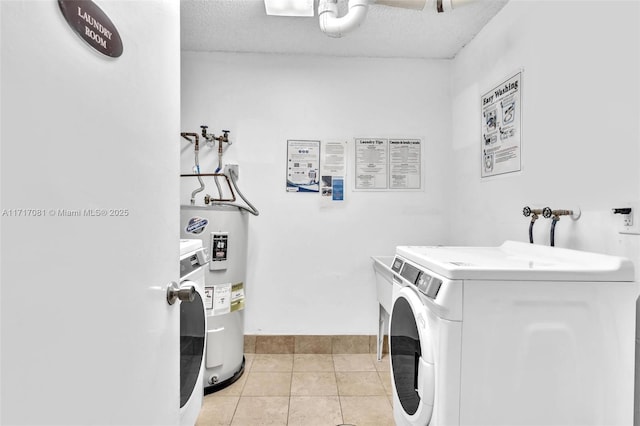 laundry area featuring electric water heater, light tile patterned floors, washer and dryer, and a textured ceiling