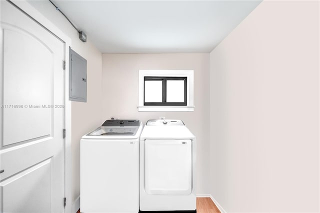 clothes washing area with electric panel, separate washer and dryer, and light wood-type flooring