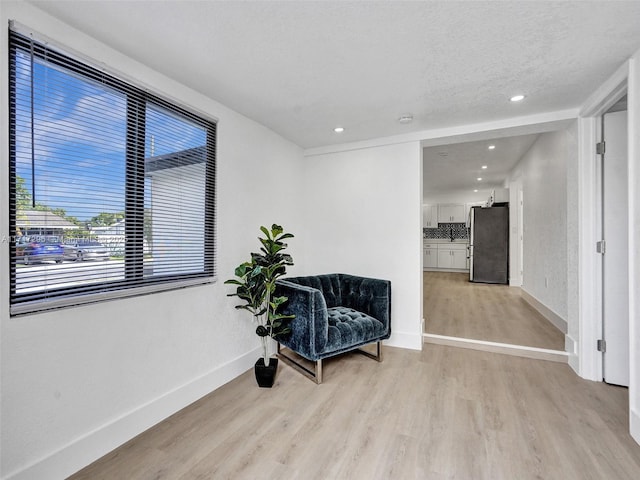 living area featuring light wood-type flooring and a textured ceiling