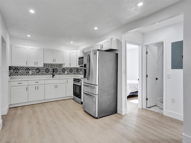 kitchen featuring stainless steel appliances, sink, light hardwood / wood-style flooring, electric panel, and white cabinetry