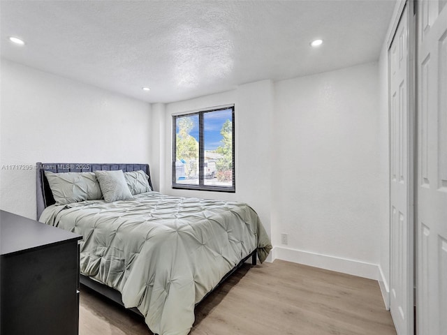 bedroom with a textured ceiling and light hardwood / wood-style flooring