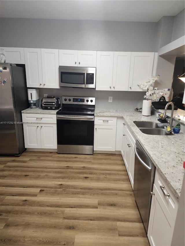 kitchen with light wood-type flooring, appliances with stainless steel finishes, white cabinets, and sink