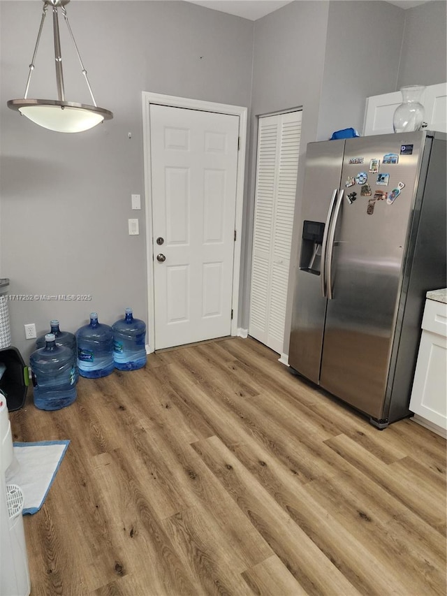 kitchen featuring light hardwood / wood-style floors, stainless steel fridge with ice dispenser, white cabinetry, and pendant lighting