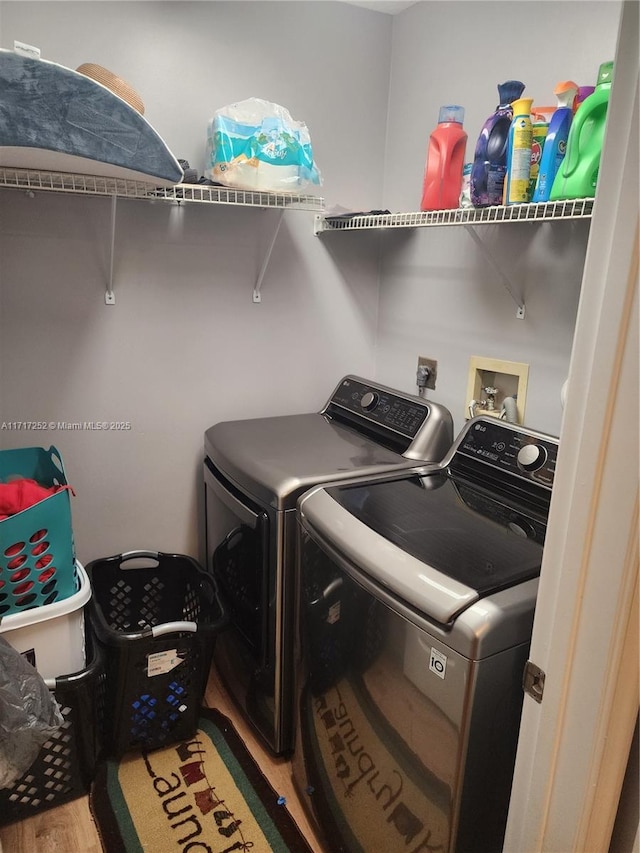 clothes washing area featuring washing machine and dryer and hardwood / wood-style floors