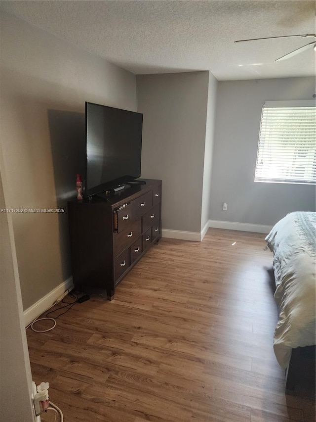 bedroom featuring a textured ceiling, ceiling fan, and light hardwood / wood-style flooring