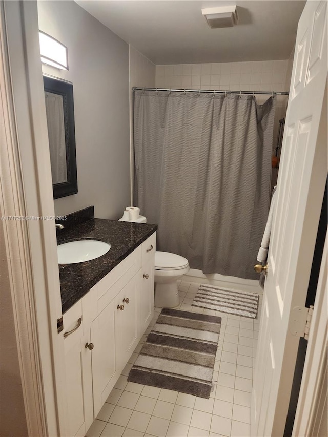 bathroom featuring toilet, tile patterned flooring, vanity, and curtained shower