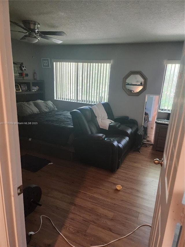 bedroom with ceiling fan, multiple windows, a textured ceiling, and hardwood / wood-style floors