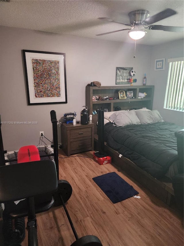 bedroom with a textured ceiling, ceiling fan, and light wood-type flooring