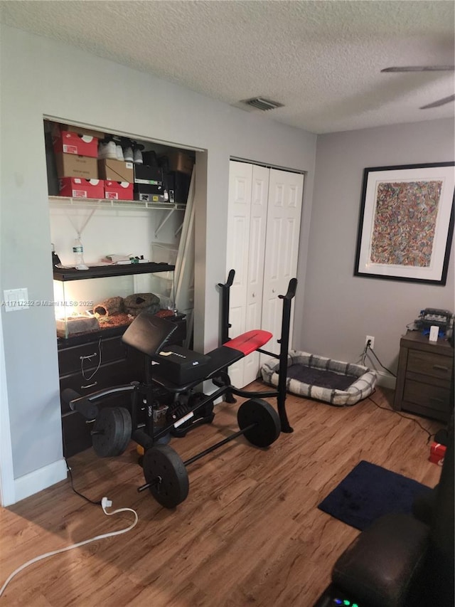 exercise room with wood-type flooring and a textured ceiling