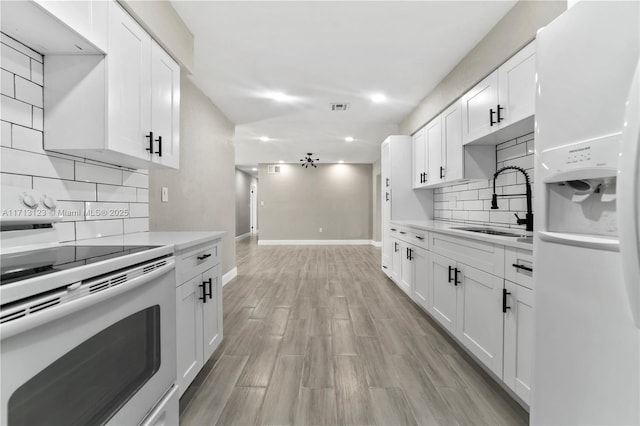 kitchen featuring tasteful backsplash, sink, white cabinets, range, and white fridge with ice dispenser