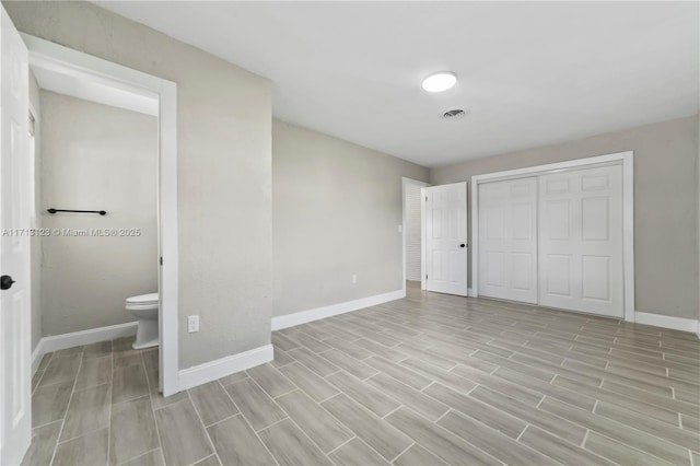 unfurnished bedroom with ensuite bath, a closet, and light wood-type flooring