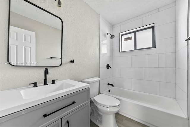 full bathroom featuring hardwood / wood-style flooring, tiled shower / bath combo, toilet, and vanity