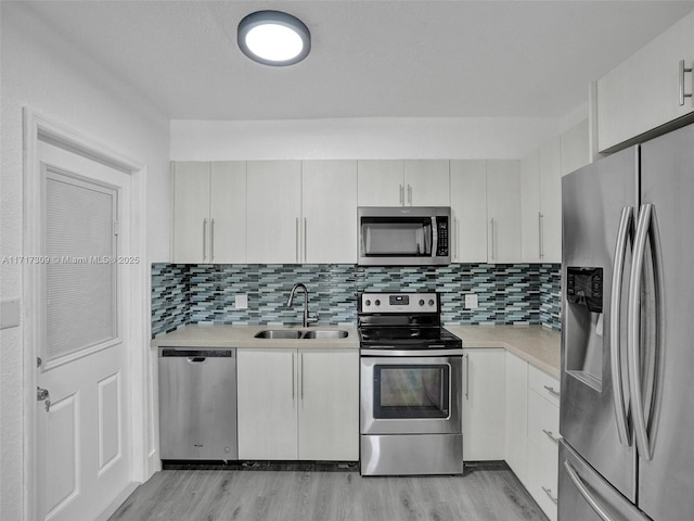 kitchen featuring stainless steel appliances, white cabinets, sink, and backsplash