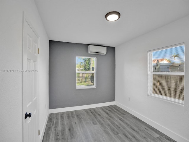 spare room with a healthy amount of sunlight, light wood-type flooring, and a wall mounted air conditioner