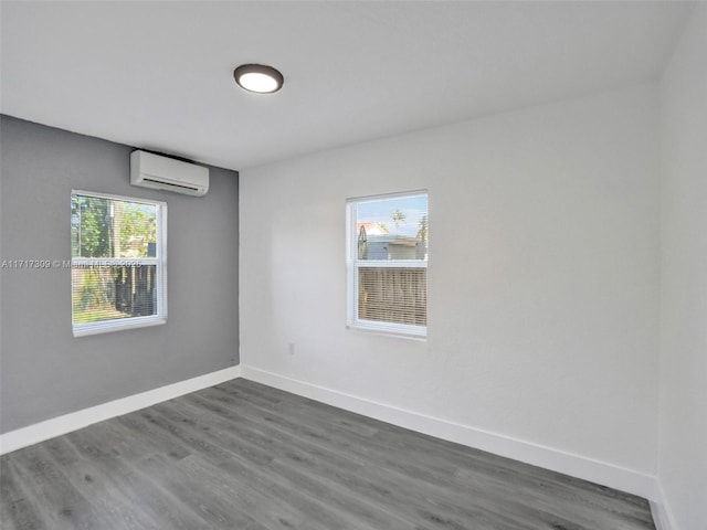 spare room featuring a wall unit AC and dark hardwood / wood-style flooring